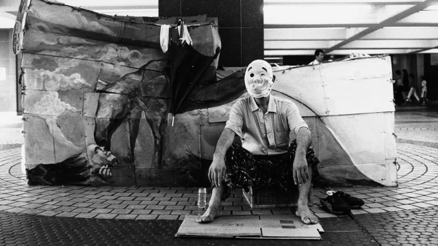 迫川尚子 お面をかぶっておどける新城さん。沖縄出身。右翼の街宣車だろうか。君が代が流れると頭をかかえてうずくまった。 1996年8月 ©迫川尚子